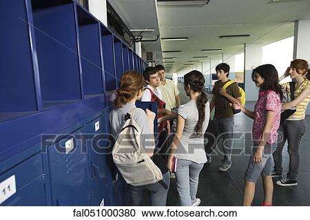 Stock Image - High school students chatting together in school corridor by lockers. Fotosearch