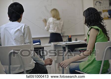 Stock Image - High school students passing notes in class. Fotosearch