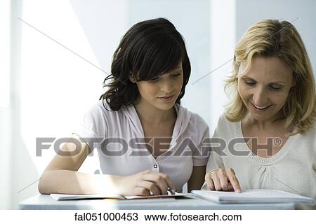 Stock Image - High school teacher and student reading notebook together. Fotosearch
