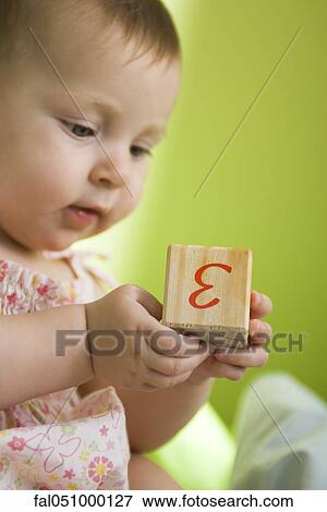 Infant girl holding wooden block View Large Photo Image Stock Photo - Infant girl holding wooden block. Fotosearch