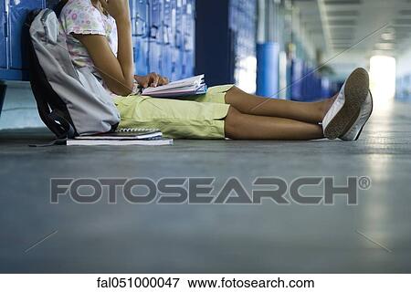 Stock Photo - Junior high student sitting on hall floor leaning against lockers reading book. Fotosearch