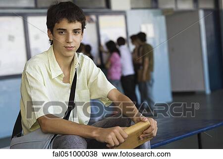 Male high school student sitting on bench holding hardback book View Large Photo Image Stock Photo - Male high school student sitting on bench holding hardback book. Fotosearch