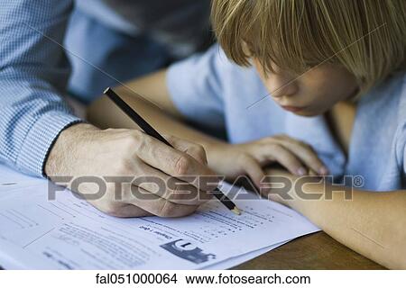Male junior high student watches as teacher corrects assignment, close-up View Large Photo Image Picture - Male junior high student watches as teacher corrects assignment, close-up. Fotosearch