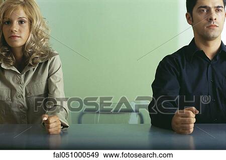 Man and woman sitting at table with empty chair between them, both clenching fists View Large Photo Image Stock Photo - Man and woman sitting at table with empty chair between them, both clenching fists. Fotosearch