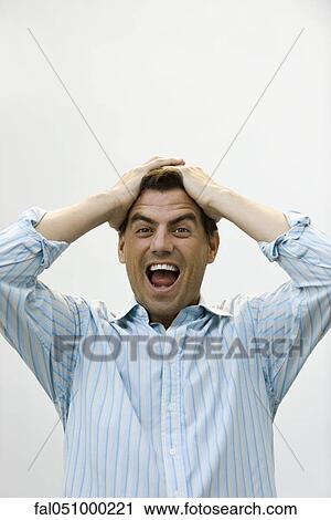 Stock Image - Man holding head screaming. Fotosearch