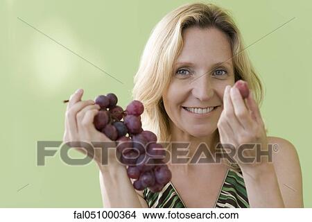 Mature woman eating grapes View Large Photo Image Picture - Mature woman eating grapes. Fotosearch