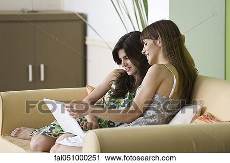 Mother and teenage daughter using laptop on sofa View Large Photo Image Stock Image - Mother and teenage daughter using laptop on sofa. Fotosearch