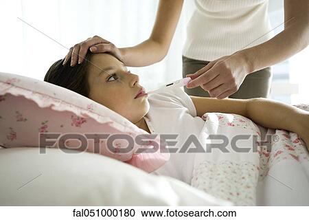 Stock Image - Mother checking daughter's temperature, caressing forehead. Fotosearch