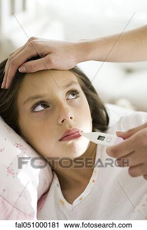 Stock Image - Mother checking daughter's temperature, caressing forehead, cropped. Fotosearch