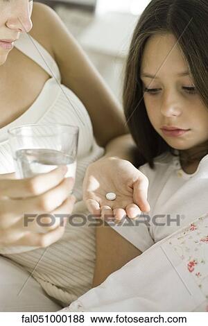 Mother giving medicine to take with glass of water to ill daughter View Large Photo Image Stock Photo - Mother giving medicine to take with glass of water to ill daughter. Fotosearch