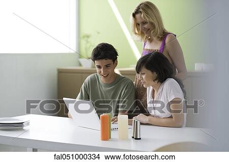 Picture - Mother observing teenage son and daughter using laptop computer. Fotosearch