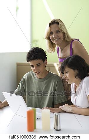 Stock Photography - Mother observing teenage son and daughter using laptop computer. Fotosearch