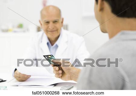 Patient handing credit card to doctor View Large Photo Image Stock Photo - Patient handing credit card to doctor. Fotosearch