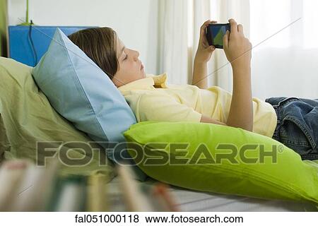 Preteen boy playing handheld video game View Large Photo Image Stock Photo - Preteen boy playing handheld video game. Fotosearch