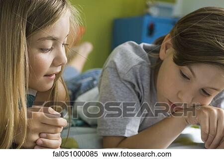 Siblings reading book together View Large Photo Image Stock Photography - Siblings reading book together. Fotosearch