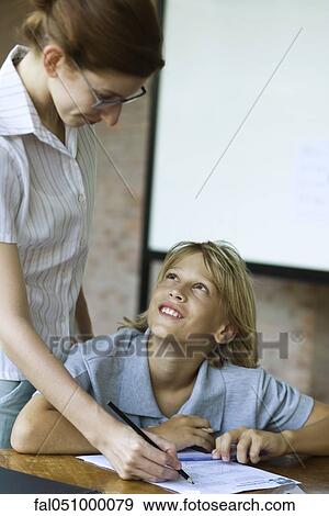Student looking up at teacher smiling as they grade their classwork View Large Photo Image Stock Photo - Student looking up at teacher smiling as they grade their classwork. Fotosearch