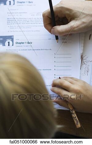 Stock Photograph - Student watching as teacher grades quiz, close-up. Fotosearch