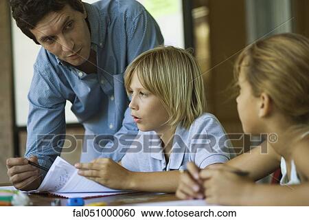 Teacher assisting students with their classwork assignments View Large Photo Image Stock Image - Teacher assisting students with their classwork assignments. Fotosearch