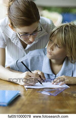 Stock Photo - Teacher correcting student's classwork, student looking up at teacher. Fotosearch