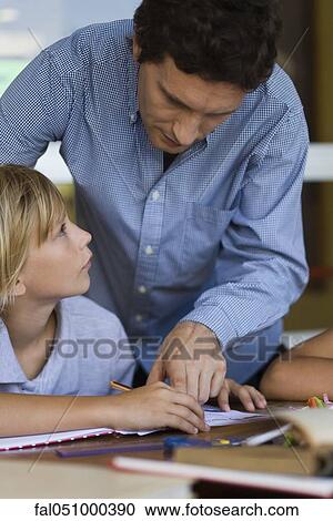 Teacher helping elementary school student in class View Large Photo Image Stock Image - Teacher helping elementary school student in class. Fotosearch