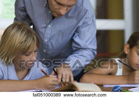 Teacher helping elementary school student in class View Large Photo Image Stock Photo - Teacher helping elementary school student in class. Fotosearch