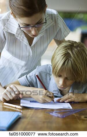 Stock Photo - Teacher looking over student's shoulder reviewing their classwork. Fotosearch