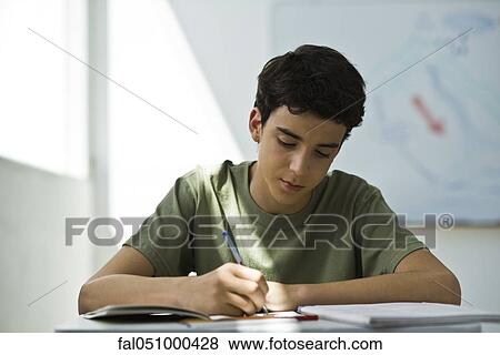 Teenage boy focusing on classwork assignment View Large Photo Image Stock Photo - Teenage boy focusing on classwork assignment. Fotosearch