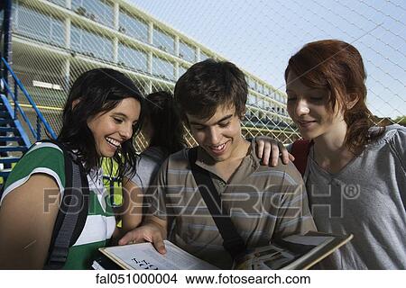 Teenage boy showing girl friends book View Large Photo Image Picture - Teenage boy showing girl friends book. Fotosearch