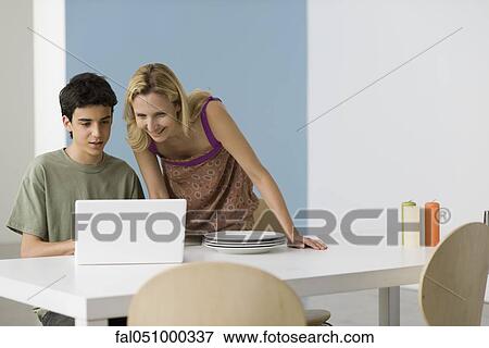 Teenage boy showing mother laptop computer View Large Photo Image Stock Photo - Teenage boy showing mother laptop computer. Fotosearch