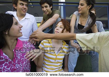 Teenage friends hanging out together placing hands on top of each other View Large Photo Image Stock Photo - Teenage friends hanging out together placing hands on top of each other. Fotosearch