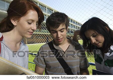 Stock Image - Teenage friends standing together chatting. Fotosearch