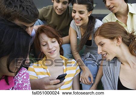 Teenage friends together, boy showing girl cell phone, others looking on with interest View Large Photo Image Picture - Teenage friends together, boy showing girl cell phone, others looking on with interest. Fotosearch