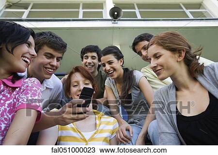 Teenage friends together, boy showing girl cell phone, others looking on laughing View Large Photo Image Stock Image - Teenage friends together, boy showing girl cell phone, others looking on laughing. Fotosearch