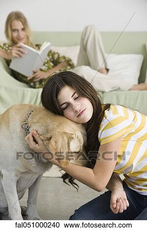 Stock Image - Teenage girl embracing pet dog. Fotosearch