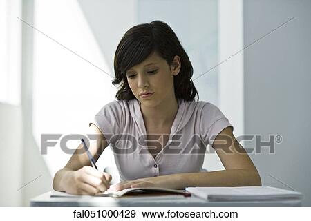 Teenage girl focusing on classwork assignment View Large Photo Image Stock Photo - Teenage girl focusing on classwork assignment. Fotosearch