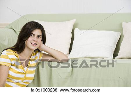 Stock Photo - Teenage girl leaning on sofa, portrait. Fotosearch