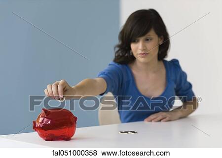 Teenage girl putting coin in piggy bank View Large Photo Image Stock Photo - Teenage girl putting coin in piggy bank. Fotosearch
