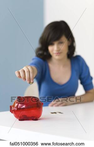 Teenage girl putting coin in piggy bank View Large Photo Image Stock Photograph - Teenage girl putting coin in piggy bank. Fotosearch