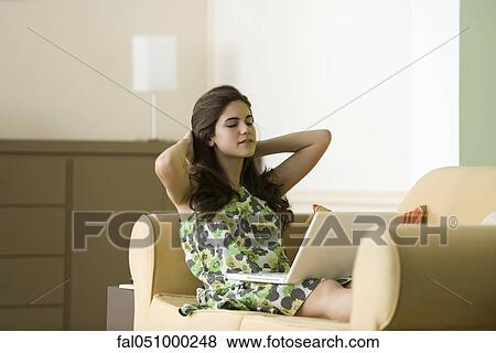 Stock Photo - Teenage girl relaxing on sofa using laptop. Fotosearch