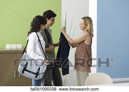 Stock Photo - Teenagers going out, mother reminding son to wear jacket. Fotosearch