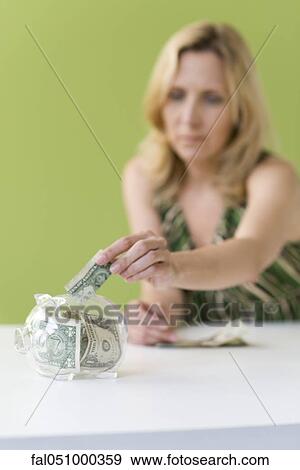 Woman putting dollar bill in piggy bank View Large Photo Image Stock Photo - Woman putting dollar bill in piggy bank. Fotosearch