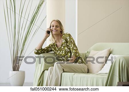 Picture - Woman relaxing in living room enjoying phone conversation. Fotosearch
