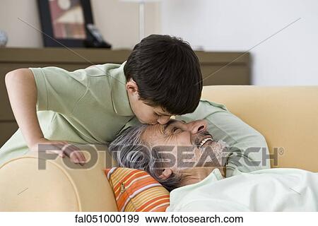 Young boy kissing napping grandfather on forehead View Large Photo Image Stock Photo - Young boy kissing napping grandfather on forehead. Fotosearch