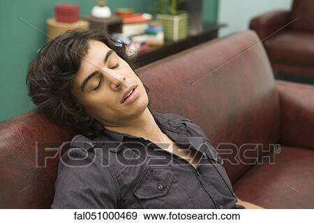 Young man dozing off to sleep on sofa View Large Photo Image Stock Photo - Young man dozing off to sleep on sofa. Fotosearch