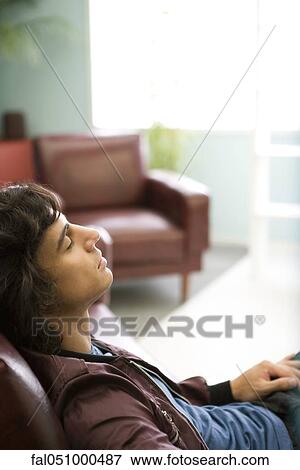 Young man relaxing on sofa View Large Photo Image Stock Photo - Young man relaxing on sofa. Fotosearch