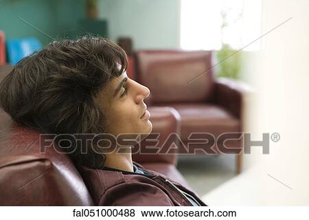 Young man relaxing on sofa View Large Photo Image Stock Photo - Young man relaxing on sofa. Fotosearch