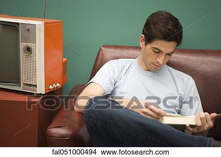 Young man relaxing with book View Large Photo Image Picture - Young man relaxing with book. Fotosearch