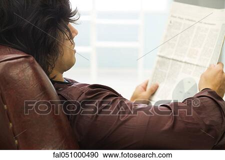 Stock Image - Young man relaxing with newspaper. Fotosearch