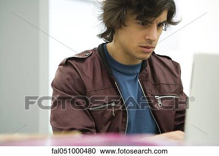 Young man using laptop View Large Photo Image Stock Image - Young man using laptop. Fotosearch
