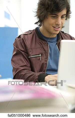Young man using laptop View Large Photo Image Stock Photograph - Young man using laptop. Fotosearch